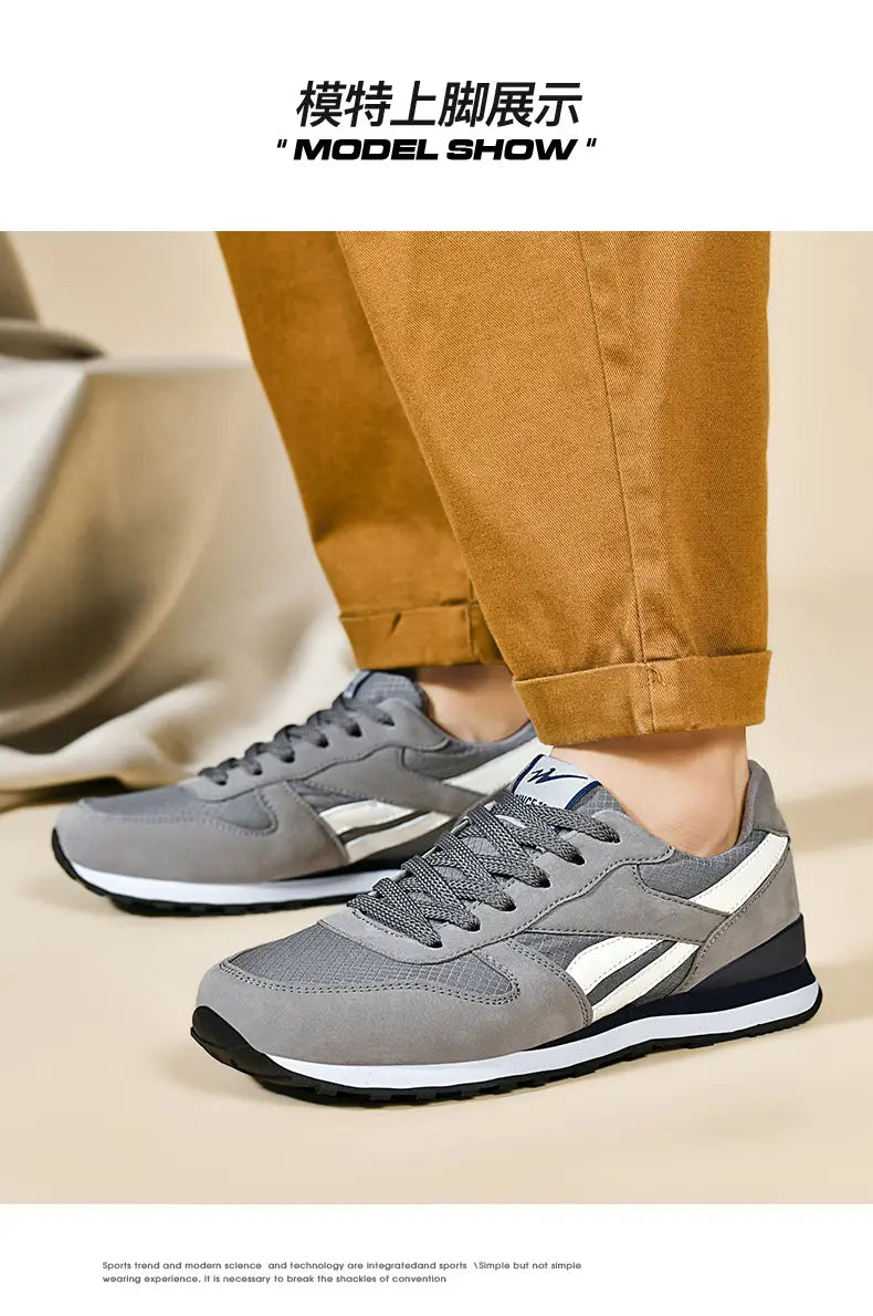 Herrenfreizeitsneaker in Grau und Weiß zum Gehen mit grauem und weißem Mesh-Obermaterial, schwarzer Gummisohle und auffälligen diagonalen Streifen an der Seite.