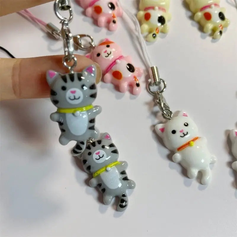Cute cat phone charm strap featuring a gray and white striped cat with black stripes, pink inner ears, a yellow collar, and a glossy resin finish.