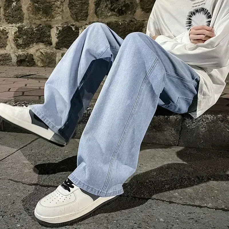 Jeans à jambes larges pour hommes, denim style streetwear coréen, présentant un denim à lavage clair avec des panneaux latéraux bleu foncé et une coupe décontractée à jambe droite.
