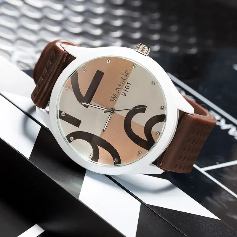 Womage silicone quartz women sports watch with a white-faced analog dial featuring a distinctive abstract geometric black beige and silver pattern and a brown leather strap.