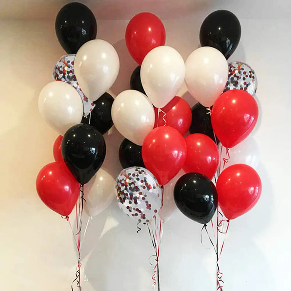 Ein Cluster glänzender Latexluftballons in Rot, Schwarz und Weiß, einschließlich einiger mit Konfetti gefüllten Innenräumen, für Partydekoration.