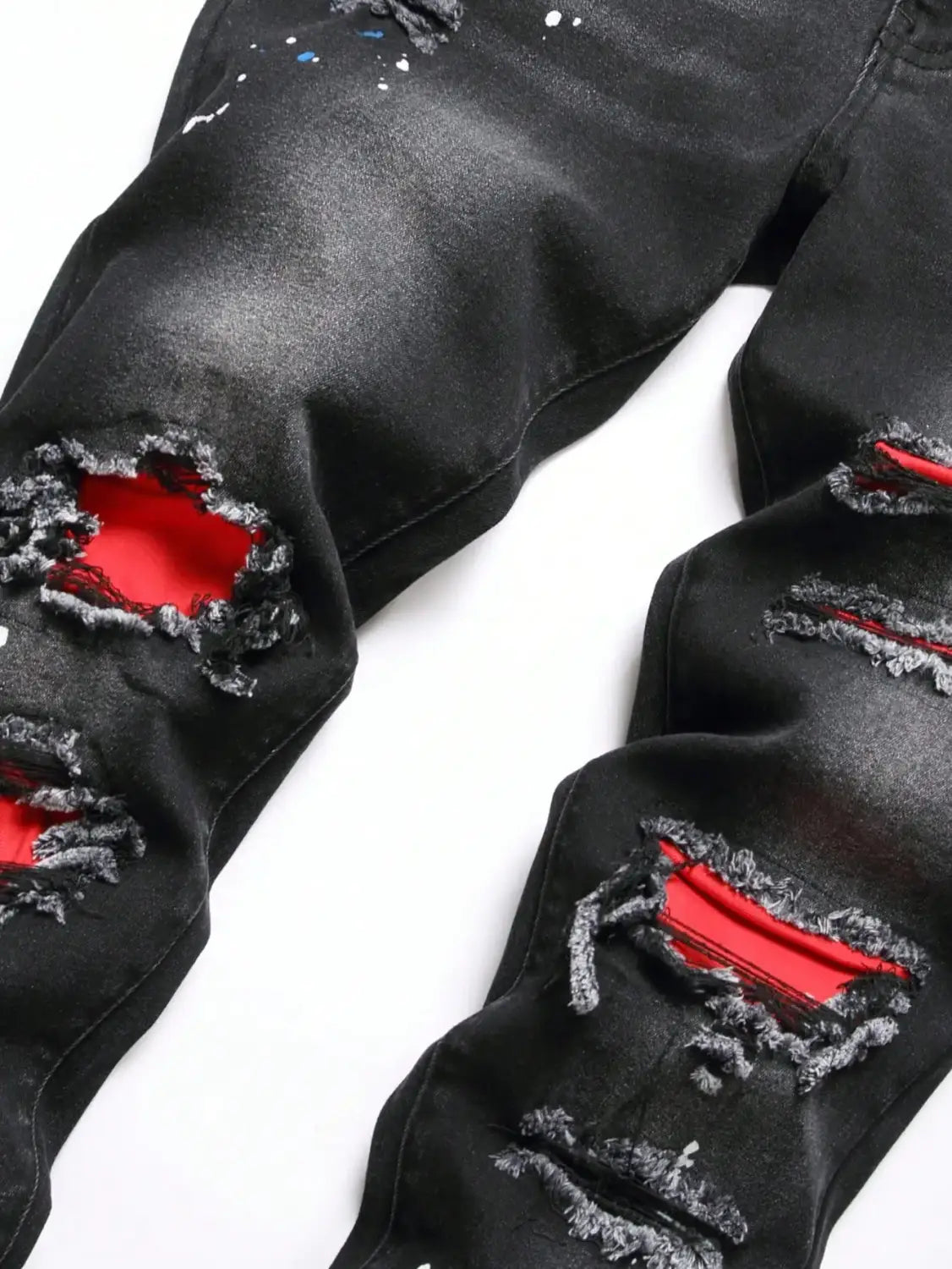 Jeans denim noirs skinny extensibles déchirés Y2K pour hommes, avec une doublure rouge intérieure marquée et des accents de peinture projetée.