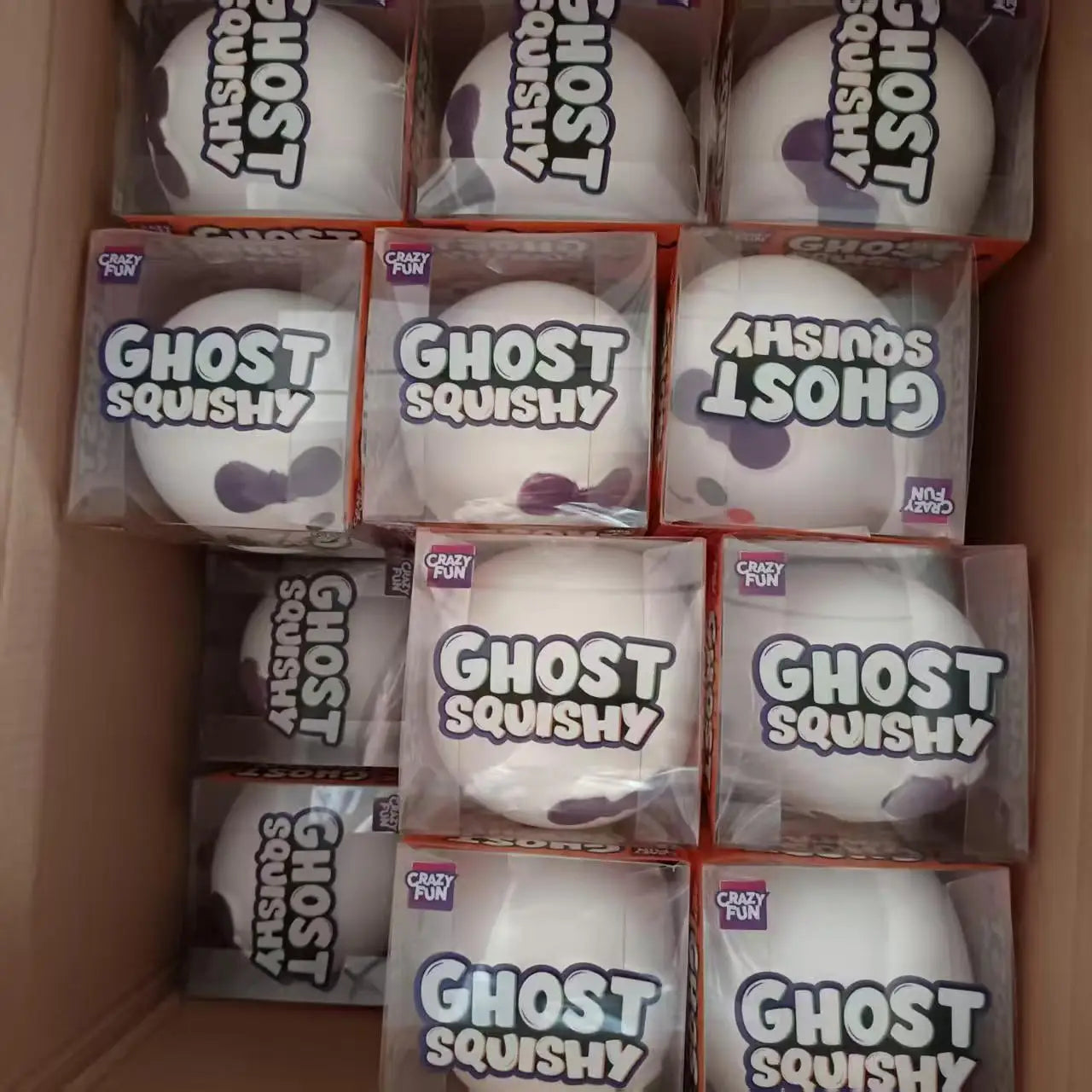 White ghost-shaped slow rising squishy stress relief toy with black eyes and purple spots packaged in clear plastic boxes labeled ghost squishy by Crazy Fun.