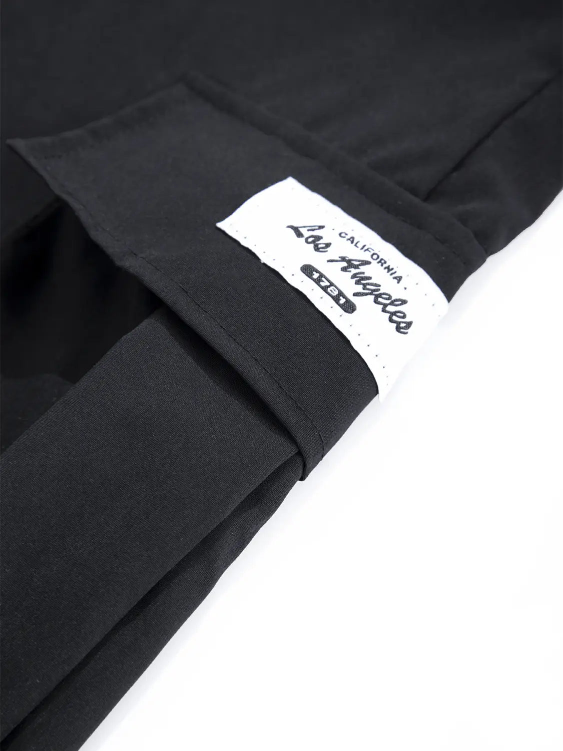 Schwarze Herren-Cargo-Hose aus Stoff, leger, mit mehreren Taschen, mit einem weißen Label auf der Rückseite, auf dem Los Angeles und 1751 in schwarzer Schreibschrift gedruckt sind.