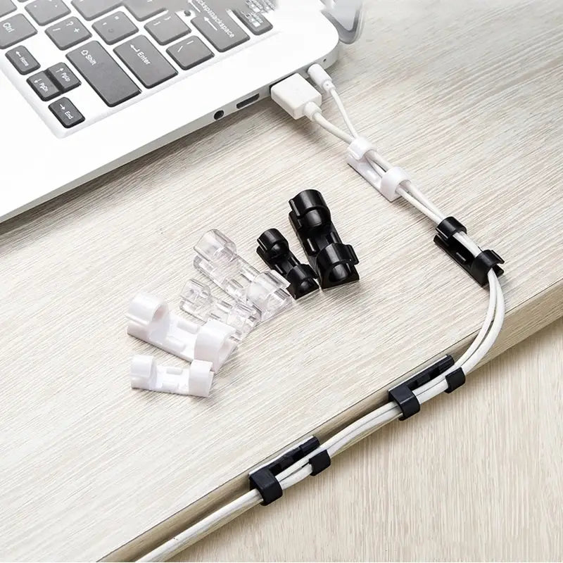 Black and clear plastic cable ties neatly organizing white usb cables on a desk using cable organizer clips desktop cord management holder.