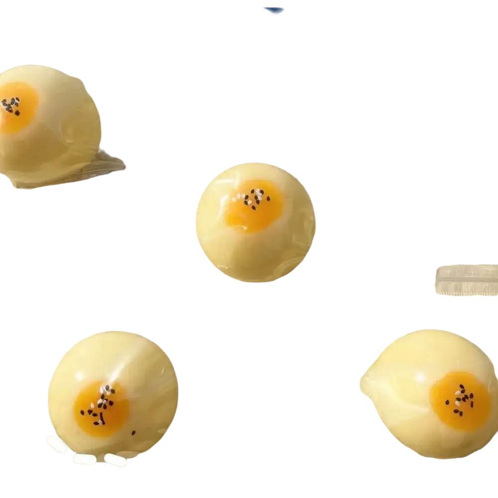 Ein durchscheinendes, gelbes, eiförmiges Silikon-Eigelb-Gebäck, langsam aufsteigend, als knetbares Spielzeug, mit orangefarbenen Zentrumstreffern und schwarzen Sprenkeln, von vorn betrachtet.