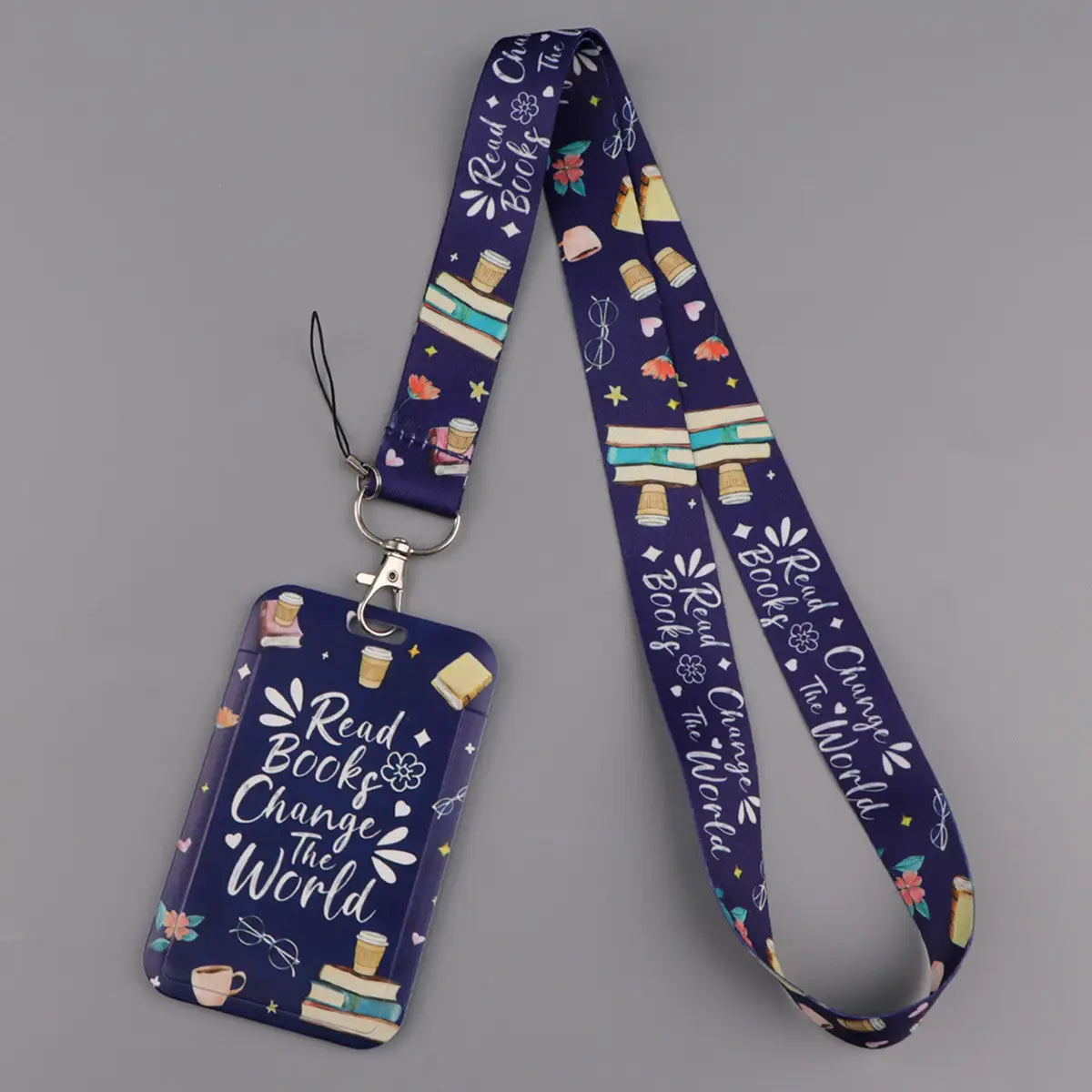 A navy blue book lover lanyard and id card holder set featuring colorful illustrations of books and coffee cups and the phrase read books change the world in white script.