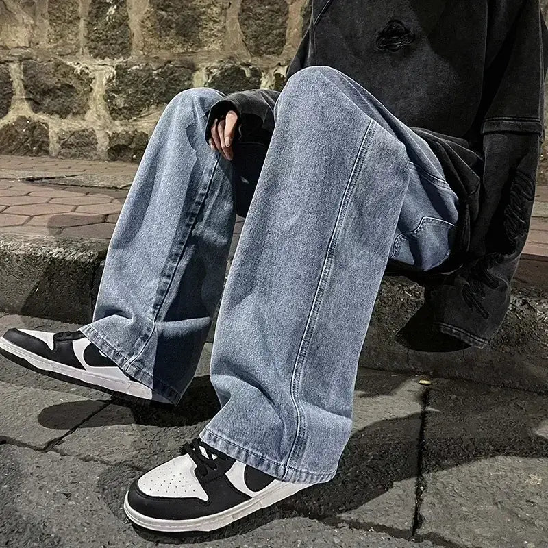 Jeans à jambes larges en denim à lavage clair pour hommes, avec une coupe décontractée à jambe droite et des détails de surpiqûres visibles dans un style streetwear coréen ample.