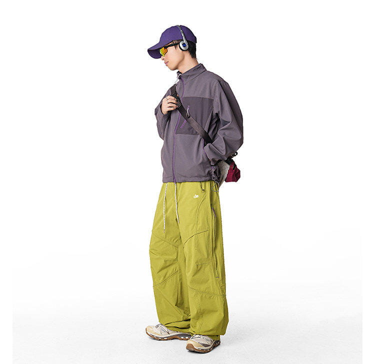una persona que viste pantalones cargo impermeables de senderismo para hombre en verde oliva de secado rápido, combinados con una chaqueta tipo bomber con cremallera gris y morado oscuro.