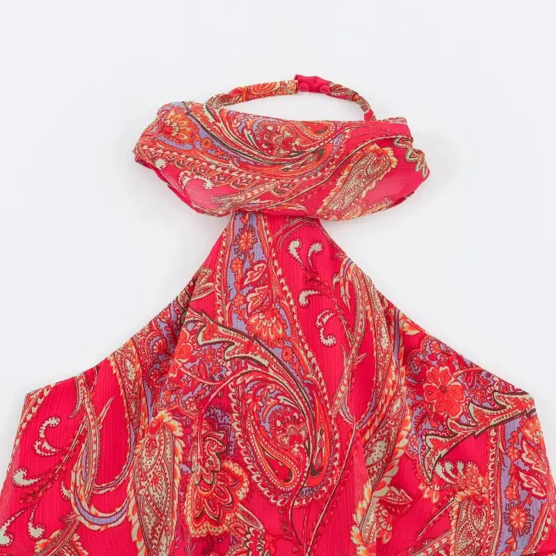A vibrant red paisley halter top dress with intricate purple and gold accents crafted from lightweight flowing fabric.