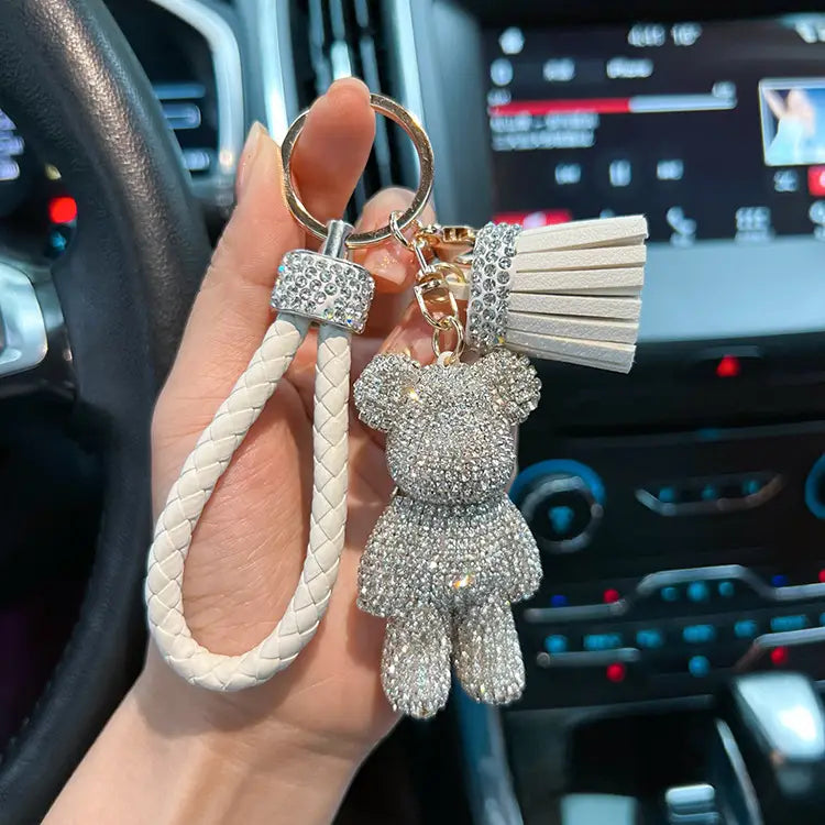 A sparkling silver rhinestone bear keychain with a braided white leather strap and matching tassel.
