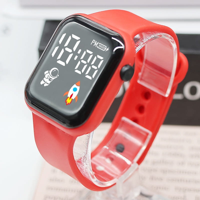 Montre électronique pour enfants à bracelet en silicone rouge, avec écran numérique noir affichant un design d’astronaute et de fusée, adaptée aux garçons et aux filles.