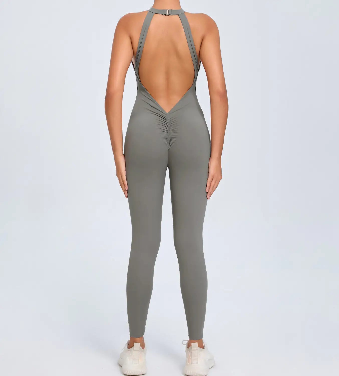 A sleek charcoal gray one-piece athletic jumpsuit with a high-neck back and ruched detailing shown from the back side designed for workout use.