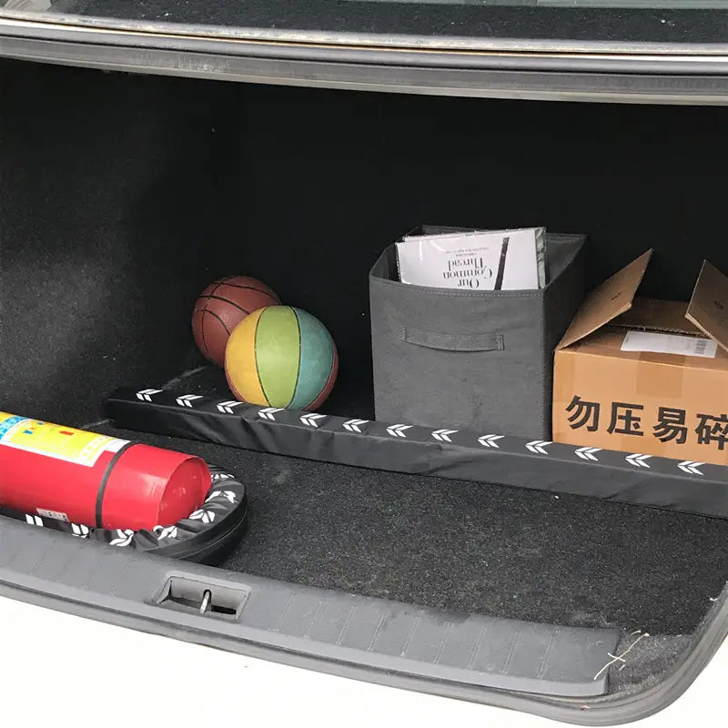 Revestimiento de carga negro con patrón de flechas blancas a lo largo del borde de un organizador flexible para el maletero del coche y una varilla de almacenamiento, para el almacenamiento y la organización del vehículo
