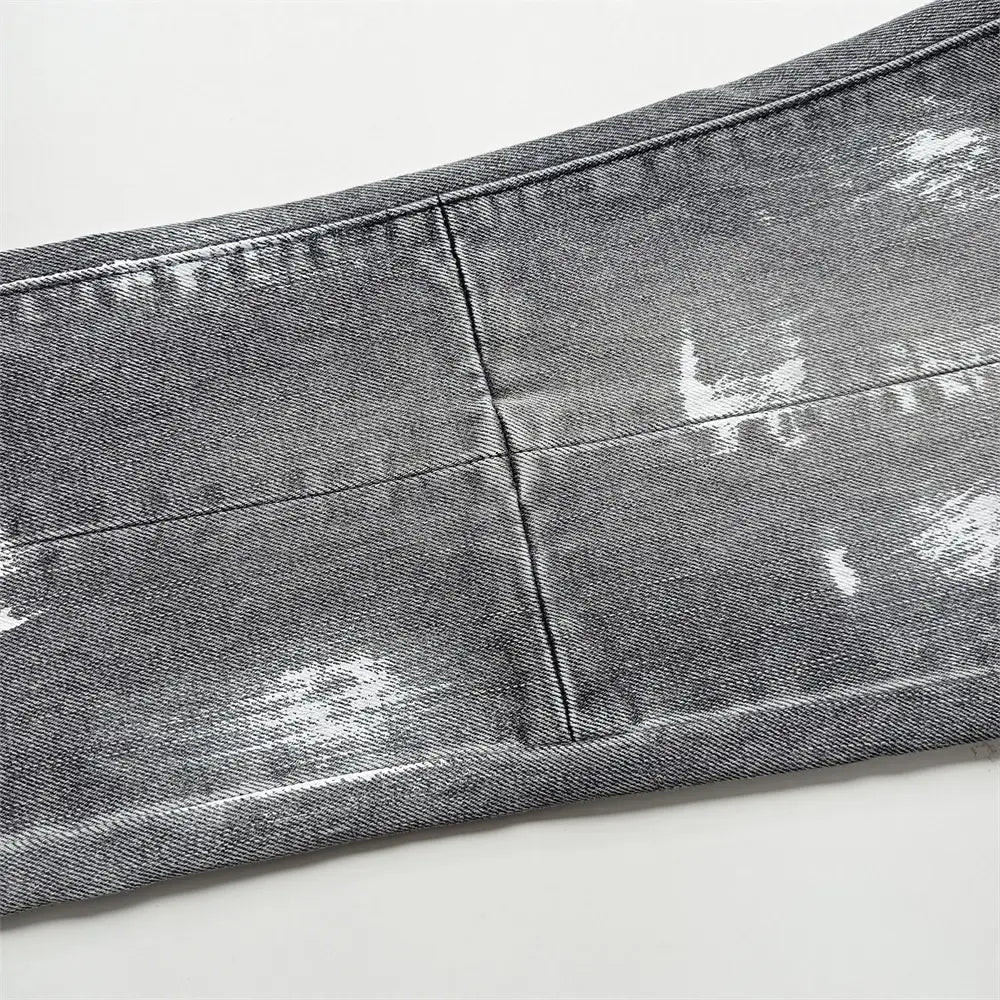 Jeans skinny déchirés pour hommes en denim gris délavé, avec effets d’éclaboussures de peinture blanche et style bleu effet délavage rétro vintage.