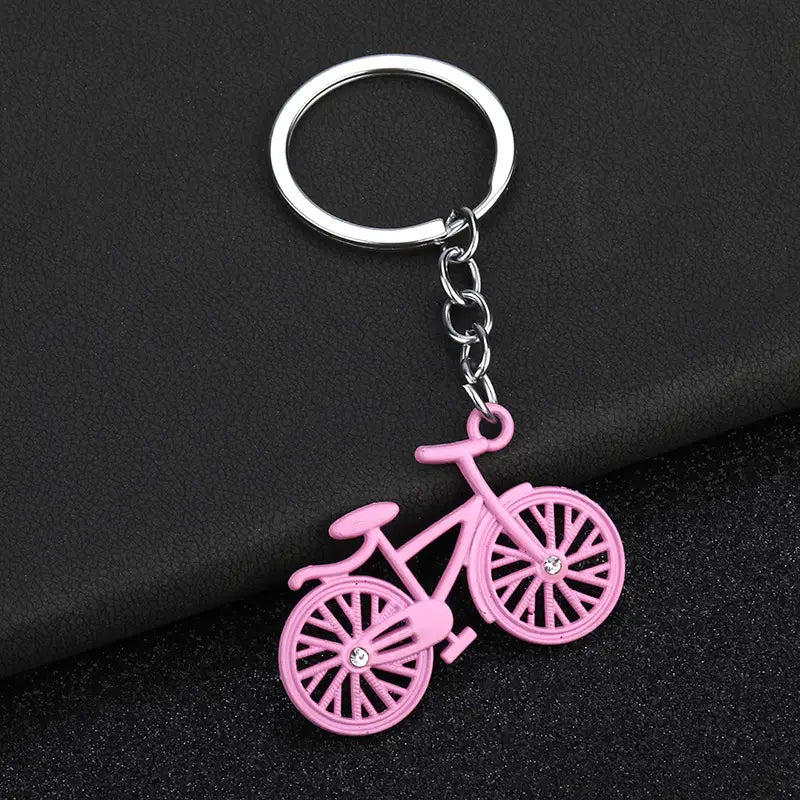 Pink bicycle keychain charm set featuring a silver metal ring and chain with small clear rhinestones on the wheels.