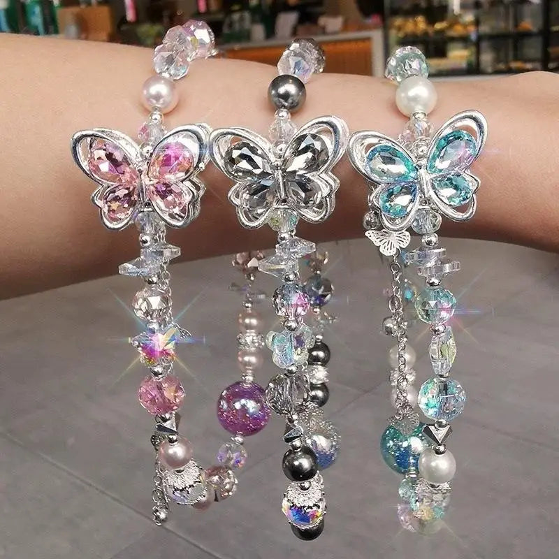 Trois charmes de chaîne pour téléphone à thème papillon scintillant avec des montures en argent métallique, des ailes en cristal coloré rose, transparent et turquoise, ainsi que des perles pendantes en verre irisé, des perles et des pierres facettées pour la décoration du téléphone mobile.