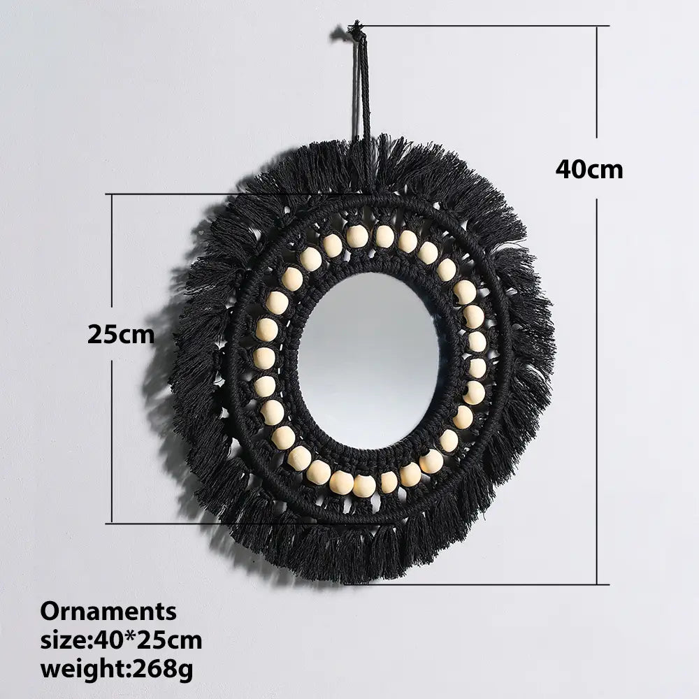 Black macrame round mirror with a circular frame adorned by cream-colored wooden beads and fringed tassels as a decorative wall mirror for boho interiors.