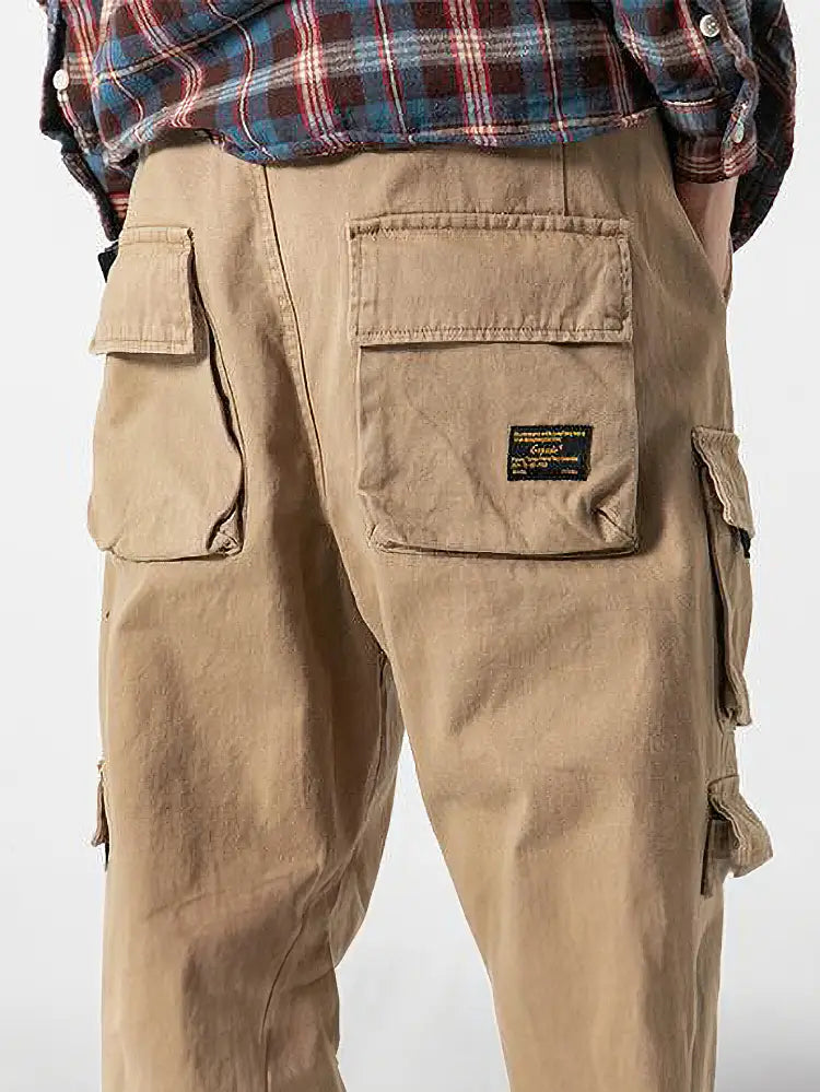 Pantalon jogger cargo coréen beige pour hommes, doté de plusieurs poches, avec une étiquette noire sur la poche arrière droite, visible depuis l’arrière.