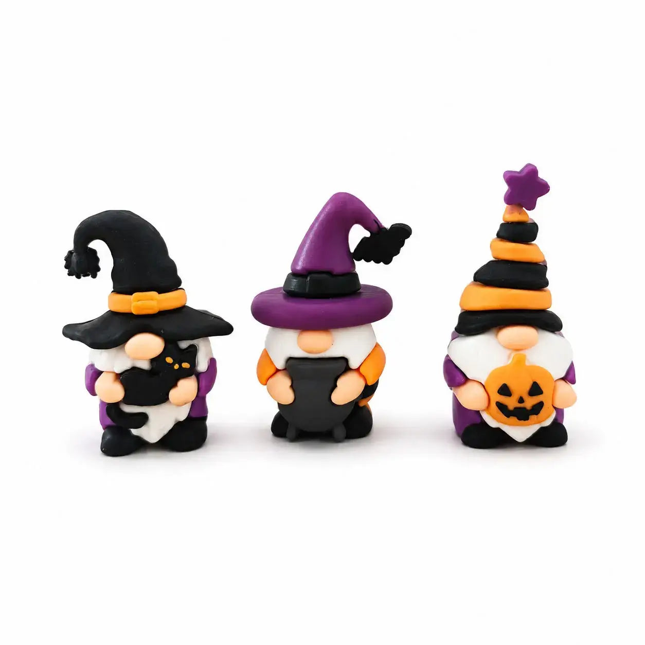 Drei Miniatur-Halloween-Gnome aus farbigem Ton mit leuchtenden Hexenhüten und festlichem Zubehör für die Halloween-Geister-Desktop-Dekoration.