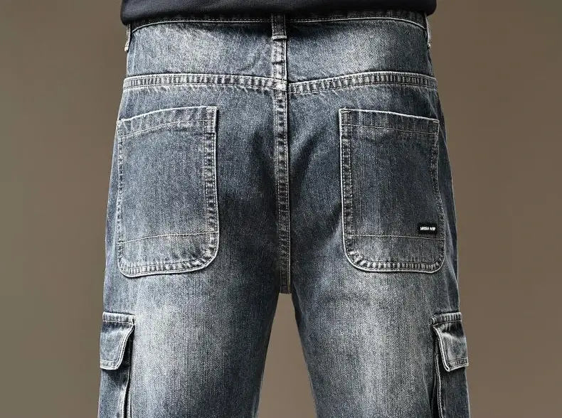 The back side of baggy dark wash denim cargo pants features reinforced stitching and a subtle brand tag on the right back pocket.