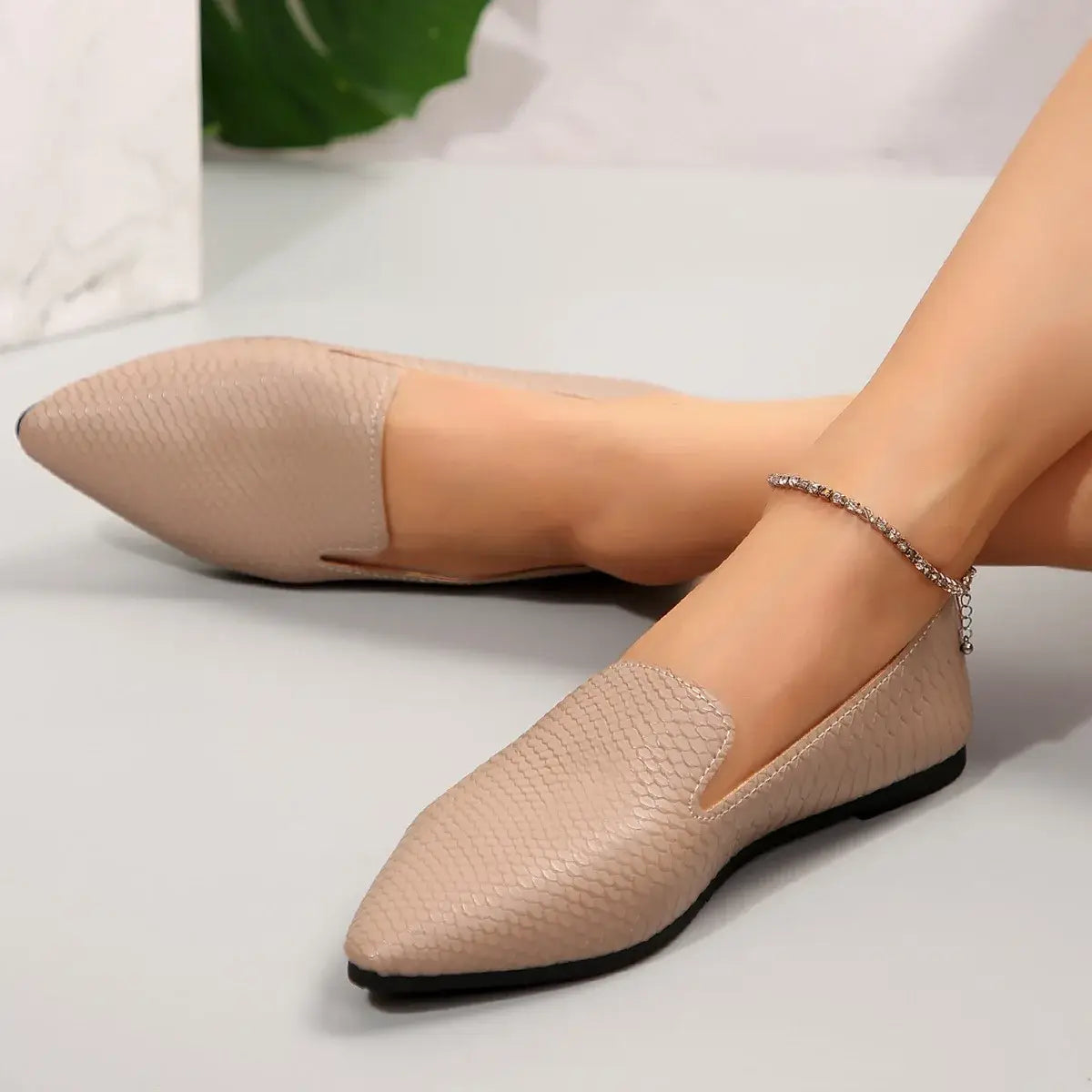 Mocasines planos de cuero color beige con estampado de piel de serpiente, punta afilada y suela de goma negra, tipo mocasín para poner y quitar con facilidad.