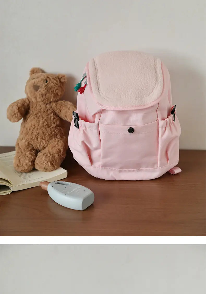 Ein weicher rosa leichter Fuzzy-Rucksack für Kinder mit plüschigem Fleece-Futter und dekorativen Patches für die Verwendung im Kindergarten.