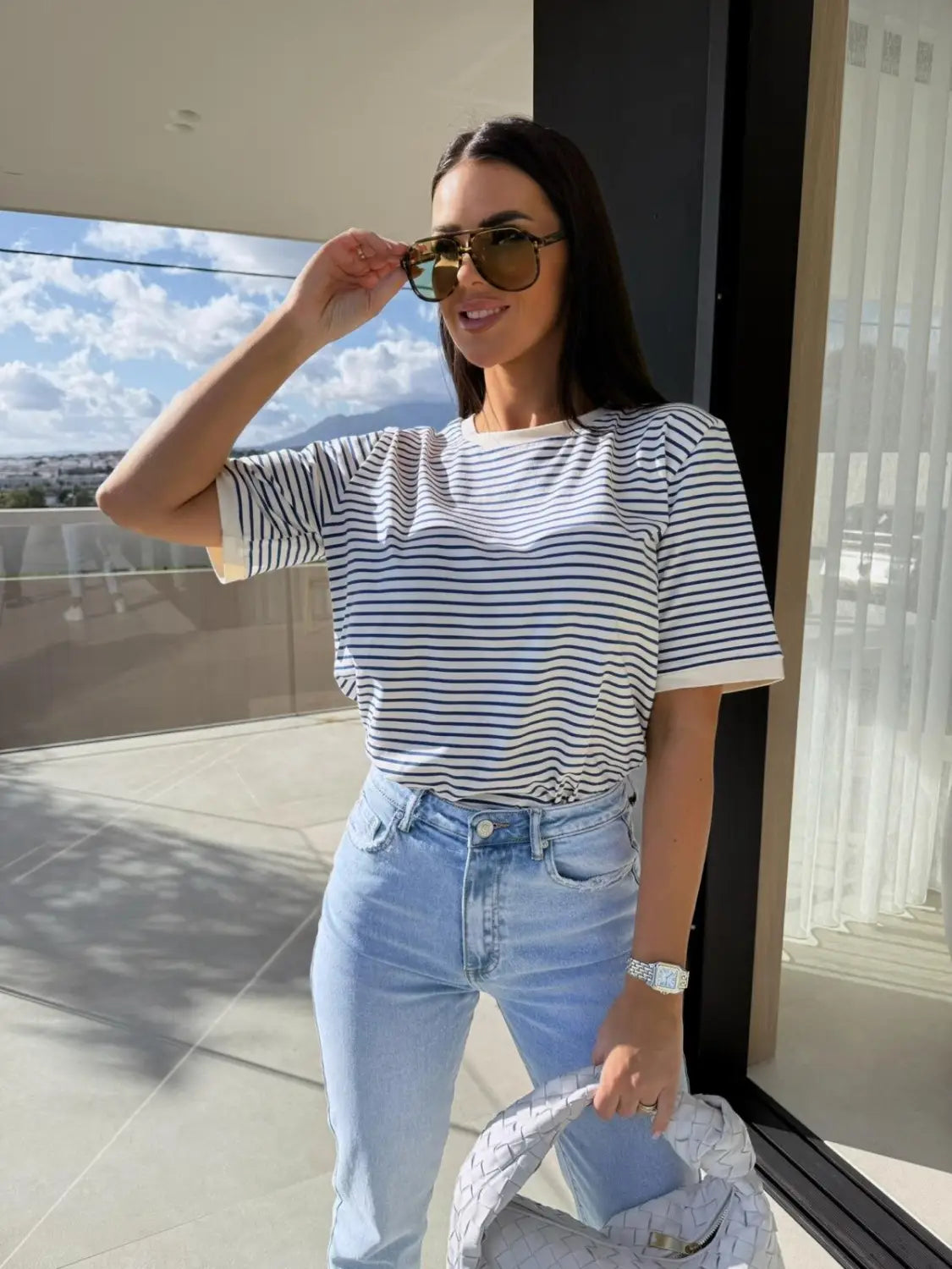 A woman wearing a navy and white striped short sleeve t shirt with rolled up sleeves suitable as a casual summer top.