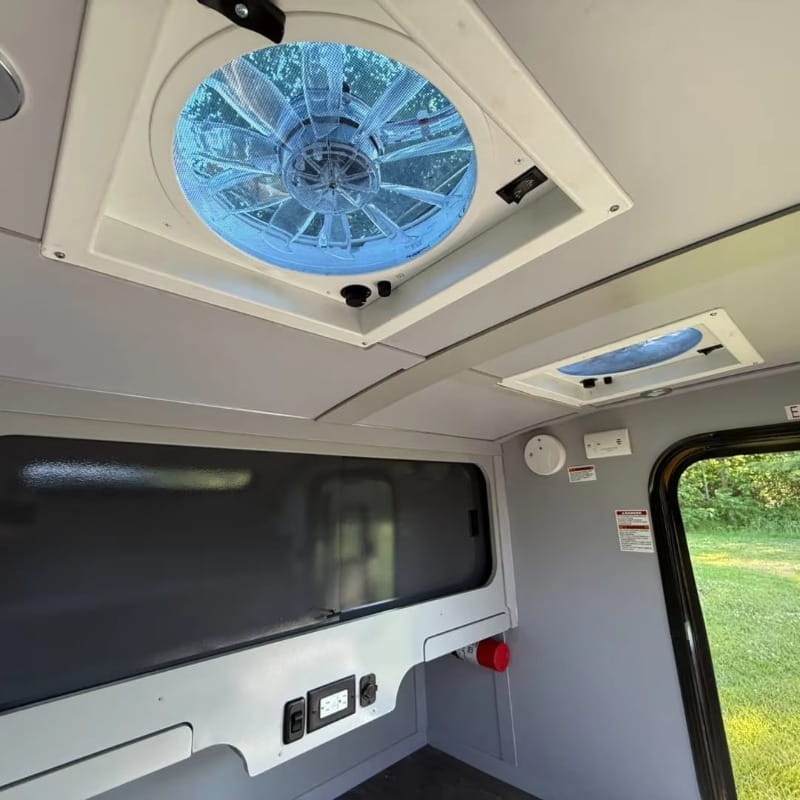 Blue circular ceiling fan with translucent ribbed design set within white rectangular housing in custom teardrop travel trailer fully equipped camper.