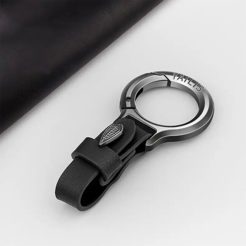 Mehrzweckiger Anti-Verlust-Halter für den Pkw-Schlüsselanhänger aus schwarzem Leder, mit elegantem metallischem Ring und eingeprägtem Logo.