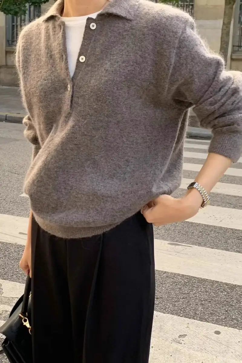 柔らかなヘザ―グレーのメリノウールVネック女性用セーターで、リラックスしたフィット感とボタン付きの襟が特徴です。