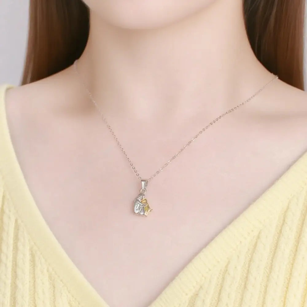 小さなツートンのデザインにイエロージェムストーンのアクセントを配した、繊細なシルバー合金の犬と女性の抱擁ペンダントネックレスです。