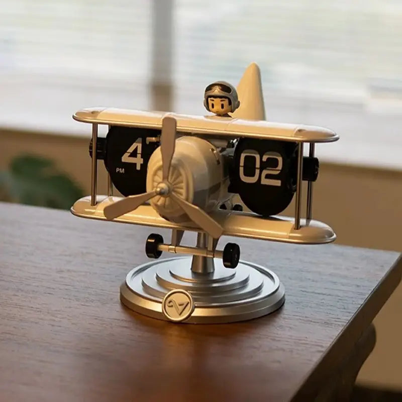 a beige and silver vintage-style airplane flip desk clock with black flip clocks displaying 402 pm on its wings and a small pilot figurine on top designed as vintage table decor
