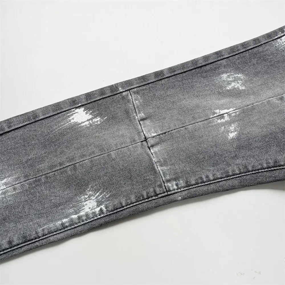 Jeans skinny déchirés pour hommes en denim gris délavé, avec accents d’éclaboussures de peinture blanche et détails en bleu de délavage rétro vintage