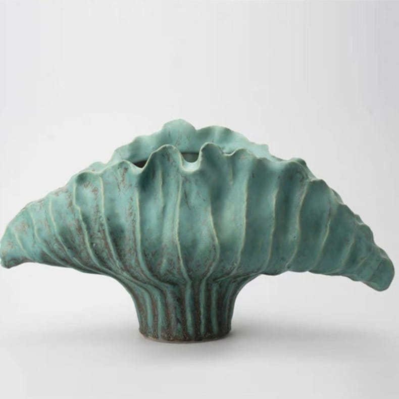 Un vase à fleurs en céramique à l’allure sculpturale, présentant une forme texturée évoquant une feuille et un émail mat turquoise, dans les dimensions 37 x 12 x 23 cm et 45 x 14 x 25 cm, conçu pour des effets d’exposition décorative modernes.