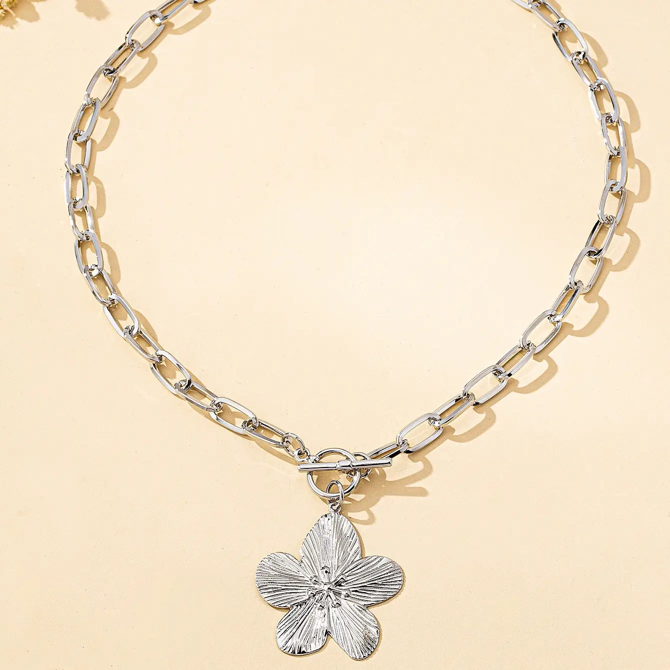 Collier pendentif à chaîne argentée présentant un pendentif de fleur de glycine à cinq pétales texturé, dans un design vintage pour femmes.