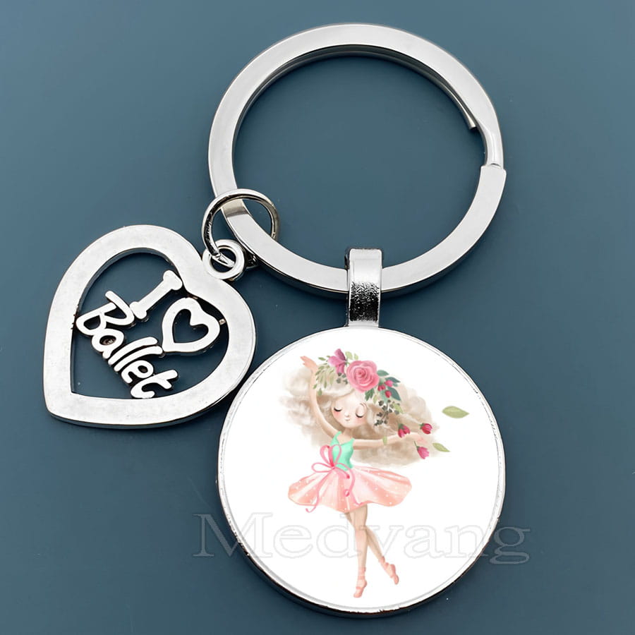 「I love ballet」と刻印された銀色のハート形チャームと、ピンクのチュチュを着たバレリーナをあしらったバレエキーチェーンのガラスドームダンサーギフト。丸いガラスペンダントを備えたデザイン。