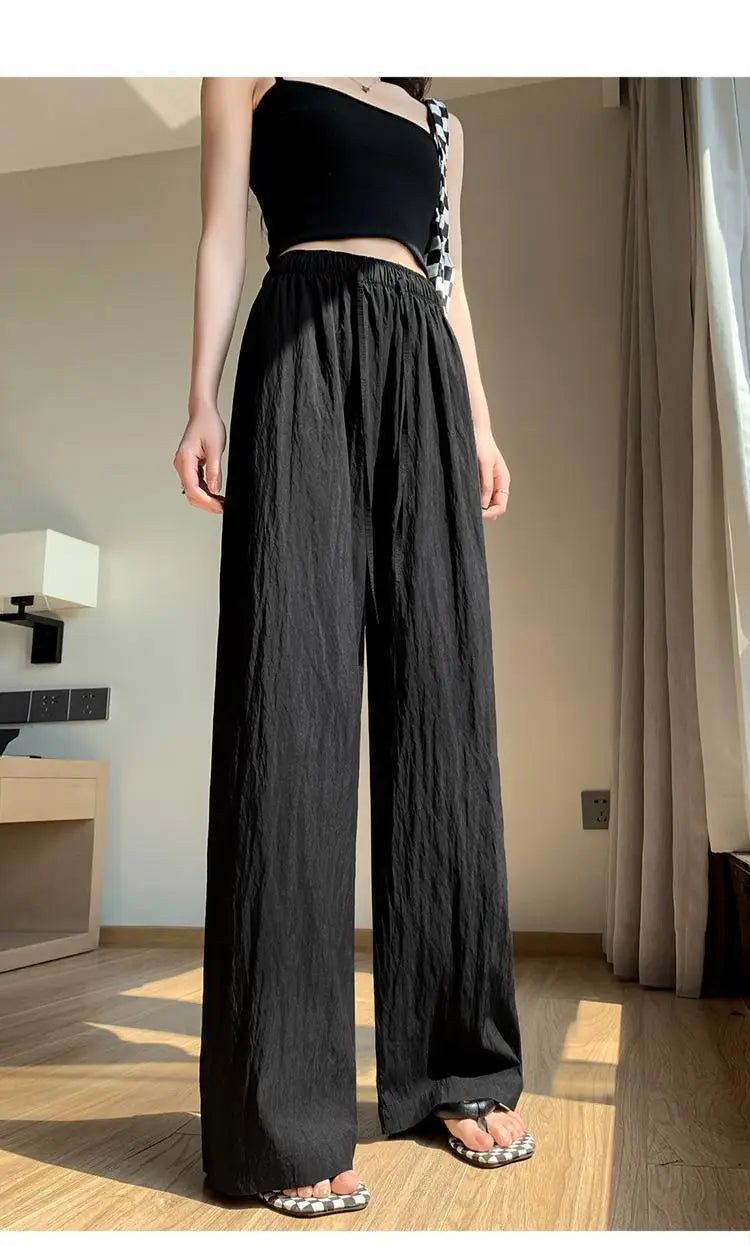 Schwarze weite Plissee-Hose für Damen mit entspannter Passform und dezenten vertikalen Falten, ideal für die Sommerzeit
