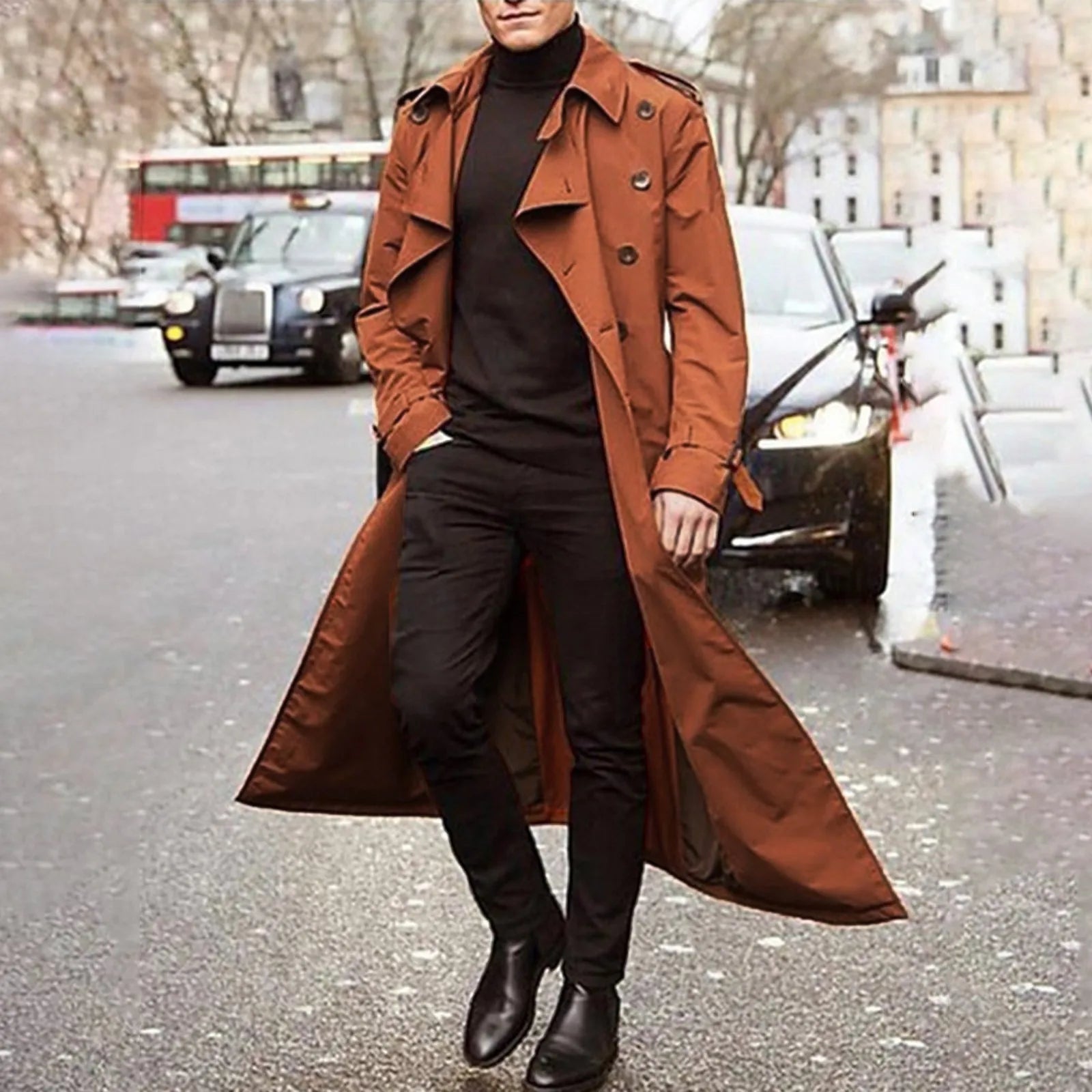 A stylish rust-colored men long trench coat with a classic double-breasted design and epaulets worn over black attire suitable for waterproof winter outerwear.