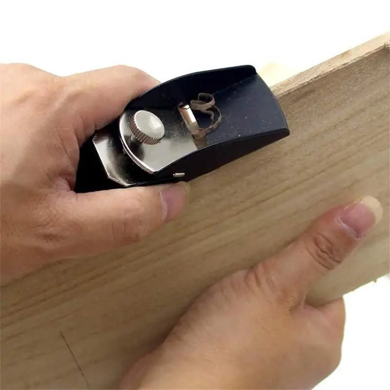 black and silver mini wood hand planer with knurled adjustment knob made of aluminum alloy resting on light-colored wood for carpentry use