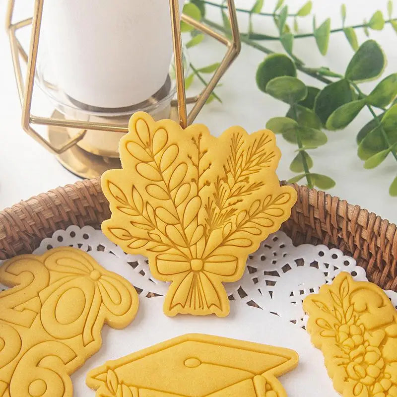 Yellow plastic graduation cookie cutter with intricate leaf and bow design from the 2026 graduation cookie cutter set.