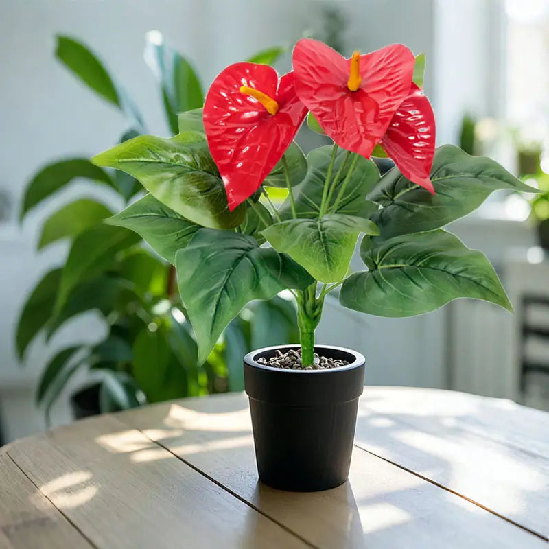 Artificial red anthurium potted plant with vibrant red flowers and glossy leaves in a sleek black ceramic pot.