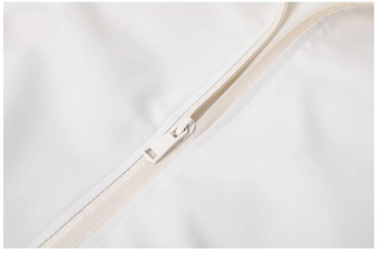 Una cremallera blanca elegante con una lengüeta metálica a juego en una chaqueta cortavientos ligera para hombre con cuello vuelto, confeccionada con tejido liso.