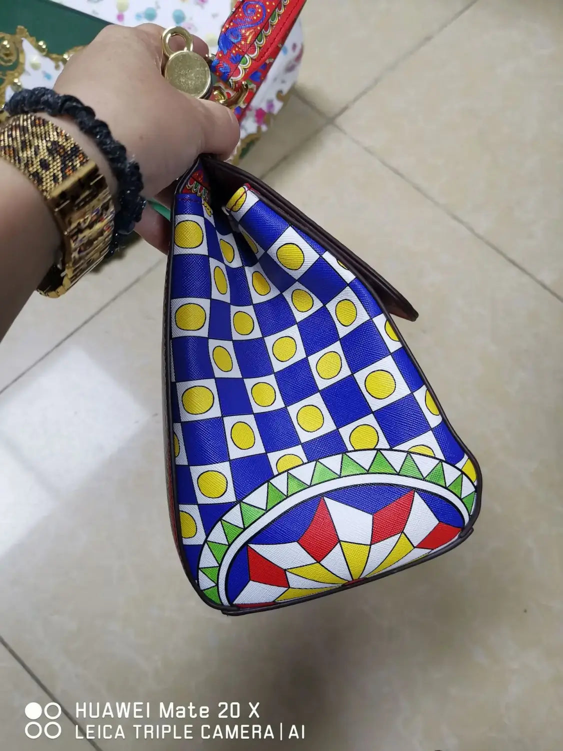 Sac bandoulière en cuir vintage, art raffiné, présentant une forme triangulaire vibrante, avec un motif à carreaux bleu et jaune très marqué, ainsi que des designs géométriques colorés le long du bord inférieur.