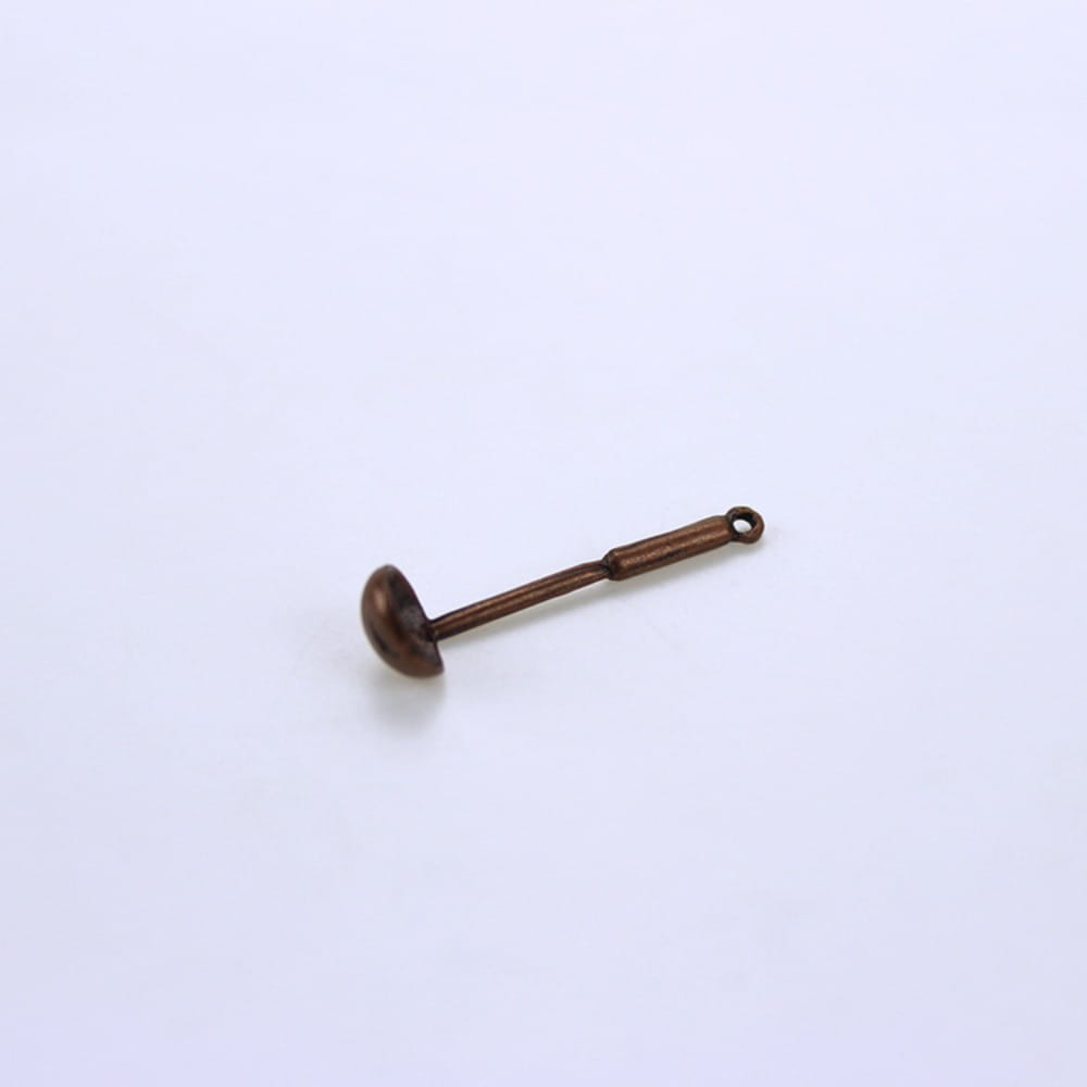 Breloque de cuillère en métal de couleur bronze antique avec une extrémité de manche bouclée, provenant d’un ensemble d’ustensiles de cuisine miniature pour maison de poupée.