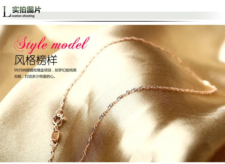Un collar delicado de cadena en oro rosa s925 de plata de ley con un diseño de eslabones trenzados finos, que forma parte de un collar de moissanita en plata de ley con tono oro rosa.