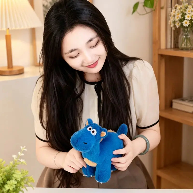 Un jouet peluche de hippopotame bleu avec des accents beige et des éléments du visage cousus, une peluche souple de la collection de peluches de dinosaure colorées.