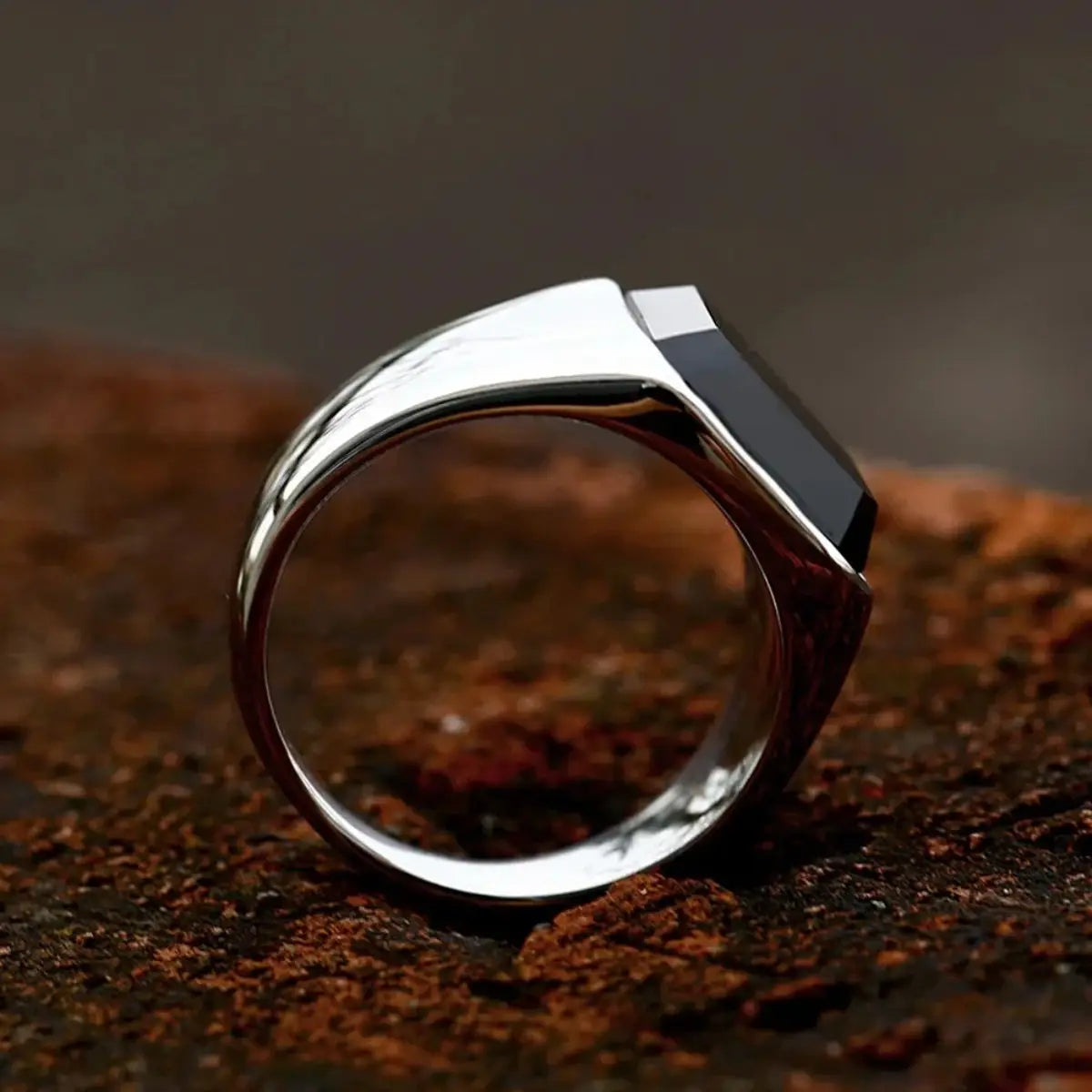 Ein eleganter schwarzer Onyx-Signetring in Silber für Damen und Herren, mit einem rechteckigen schwarzen Onyx-Stein, der in einem markanten modernen Band eingefasst ist.