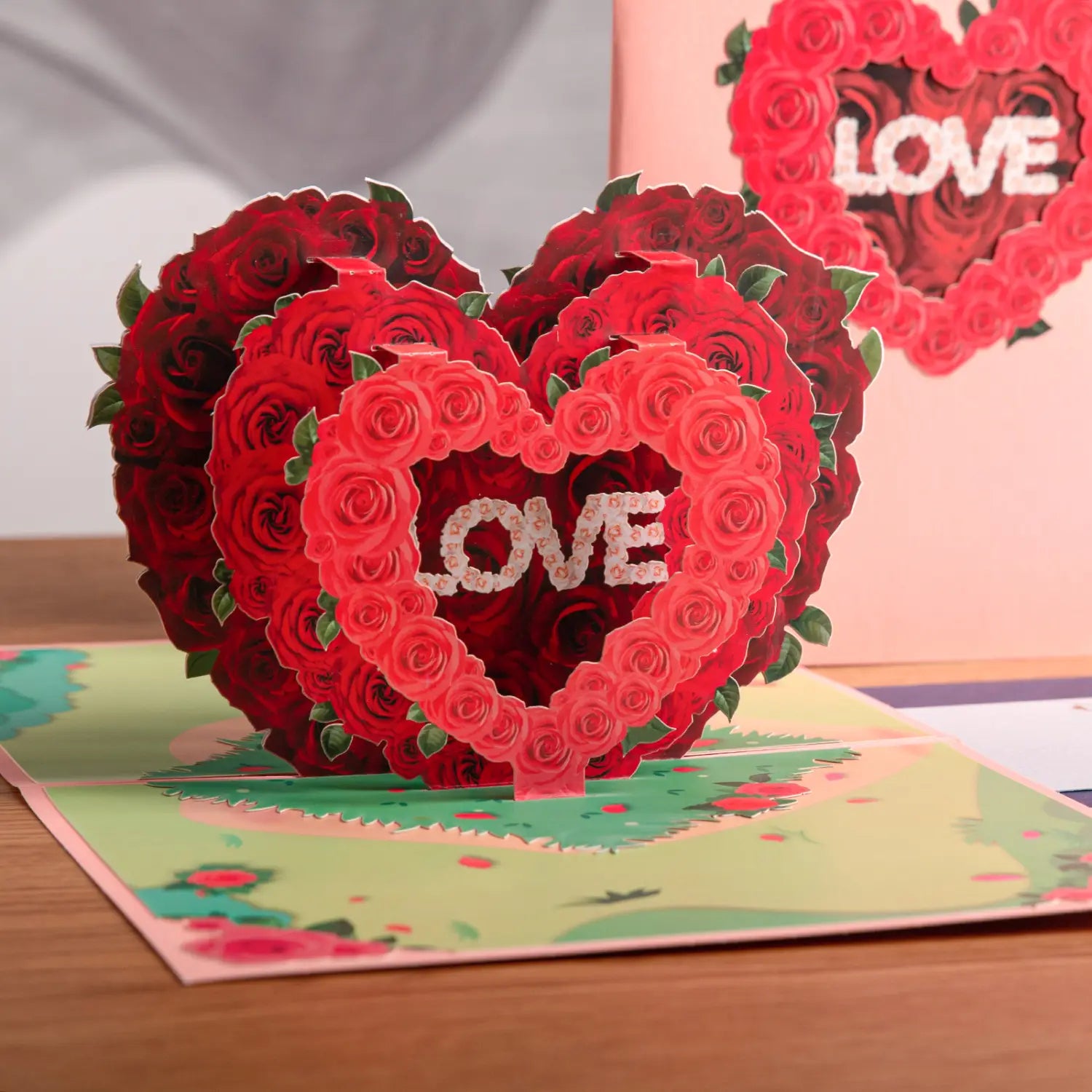 Carte de la Saint-Valentin 3D à effet pop-up vibrante rouge, avec des roses en papier finement superposées formant une forme de cœur, le mot « love » étant inscrit au centre en lettres scintillantes.