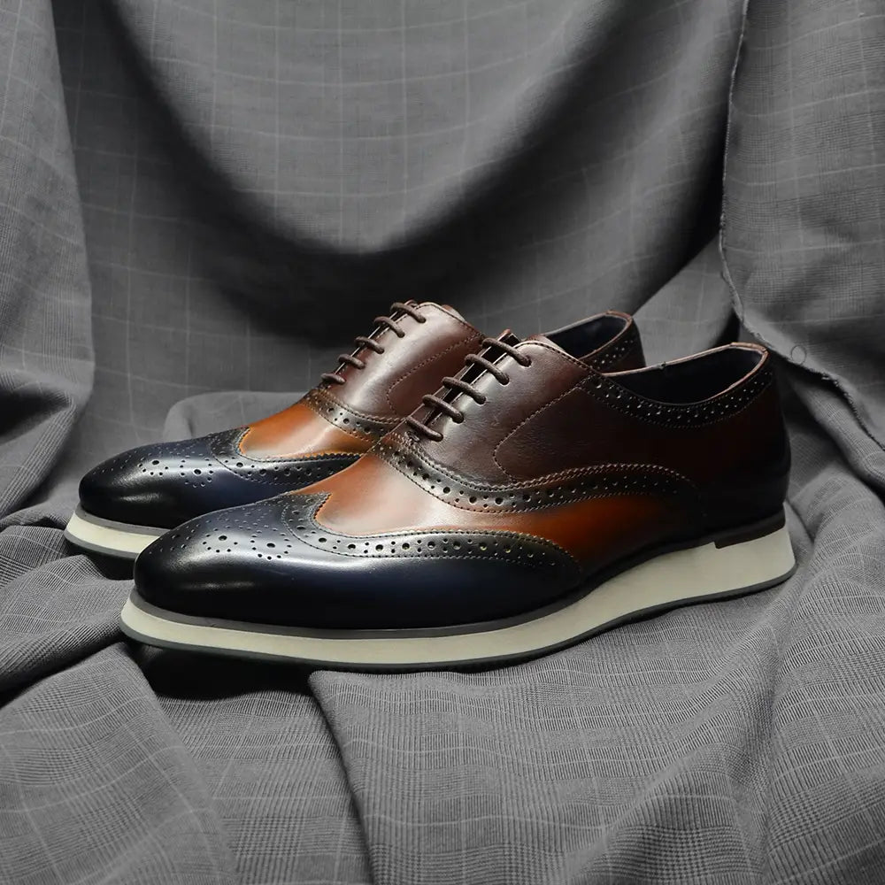 Escarpins brogue wingtip Oxford bicolores marron et noir, avec des détails ajourés.